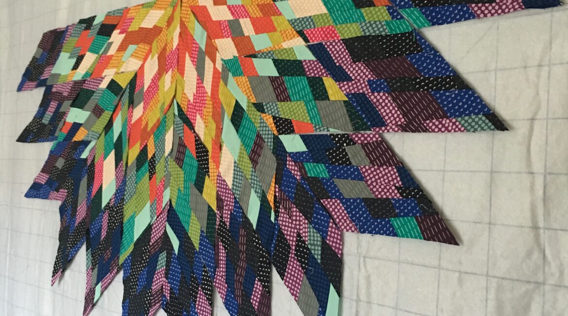 A colorful flower quilt hanging on a wooden wall