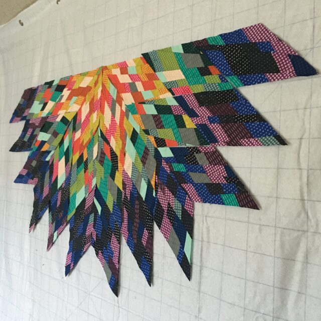 A colorful flower quilt hanging on a wooden wall