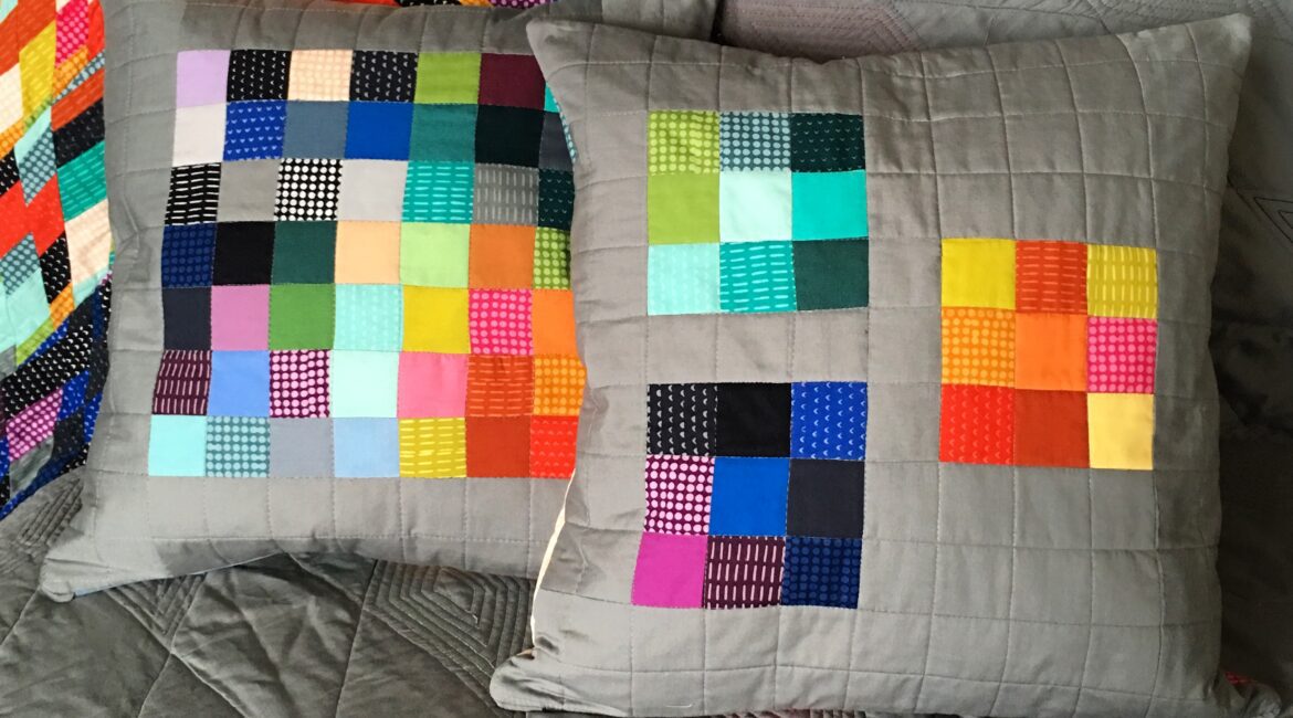 Two pillows with colorful squares on them.
