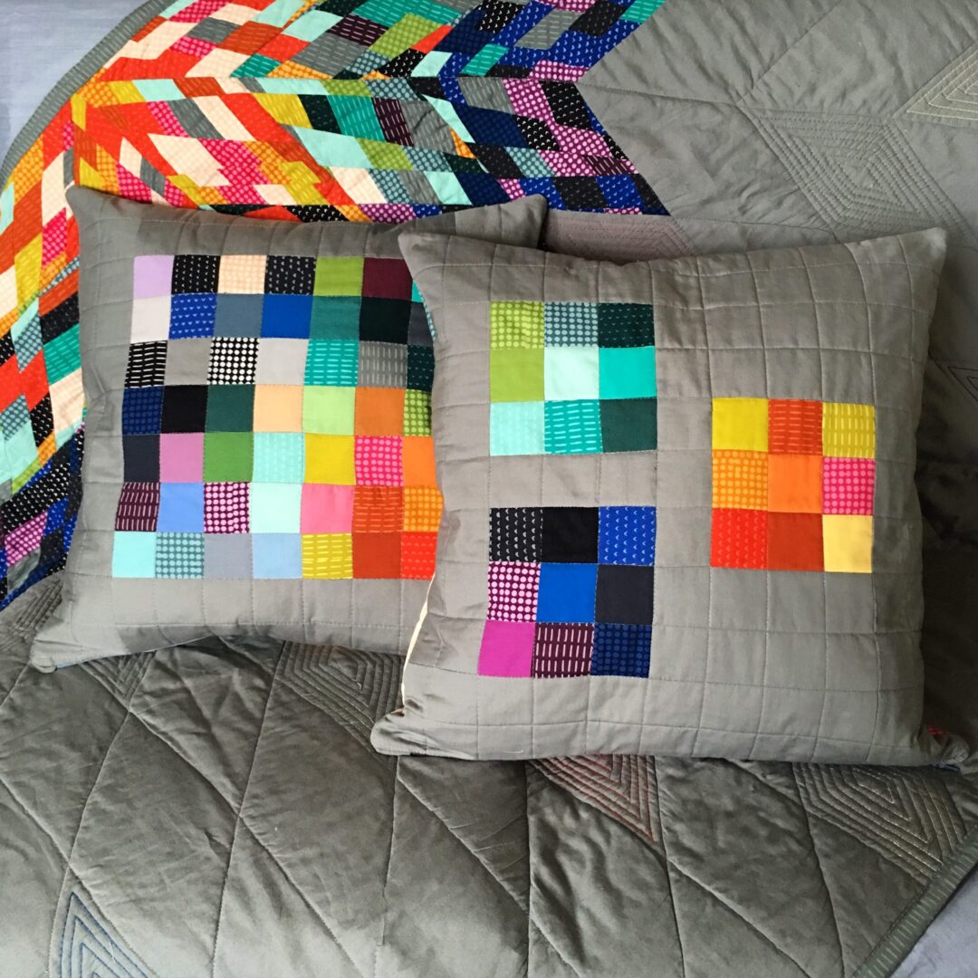 Two pillows with colorful squares on them.