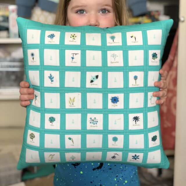 turquoise pillow with white squares filled with plants