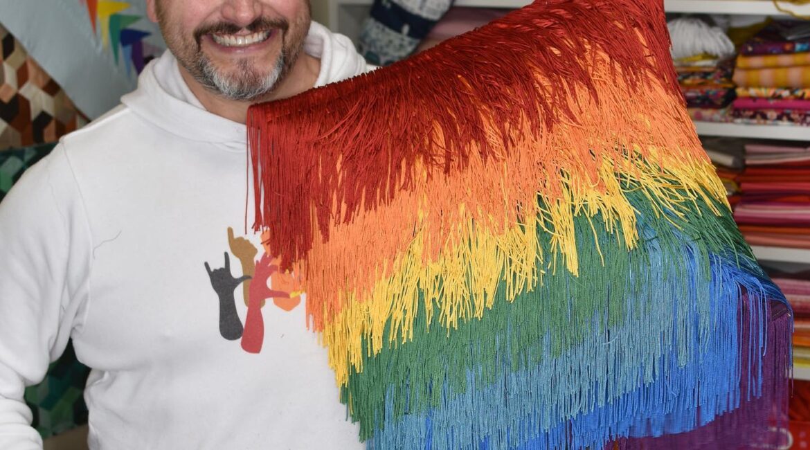 Mathew holding a fringed and rainbow-colored pillow case  